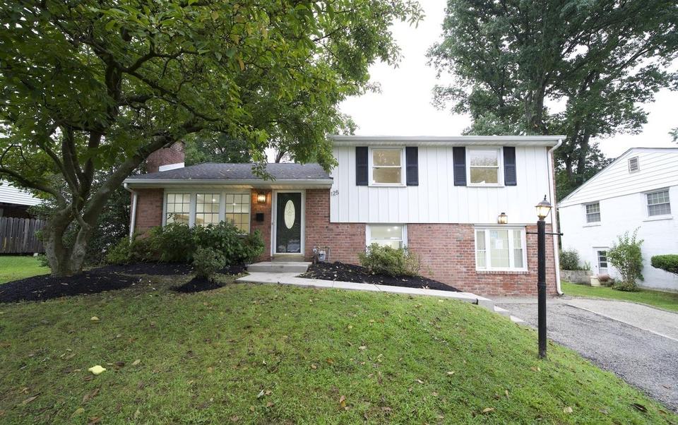 Front exterior of 125 W Thomson Avenue: a brick and white-sided split-level home with black shutters and a mature shade tree.