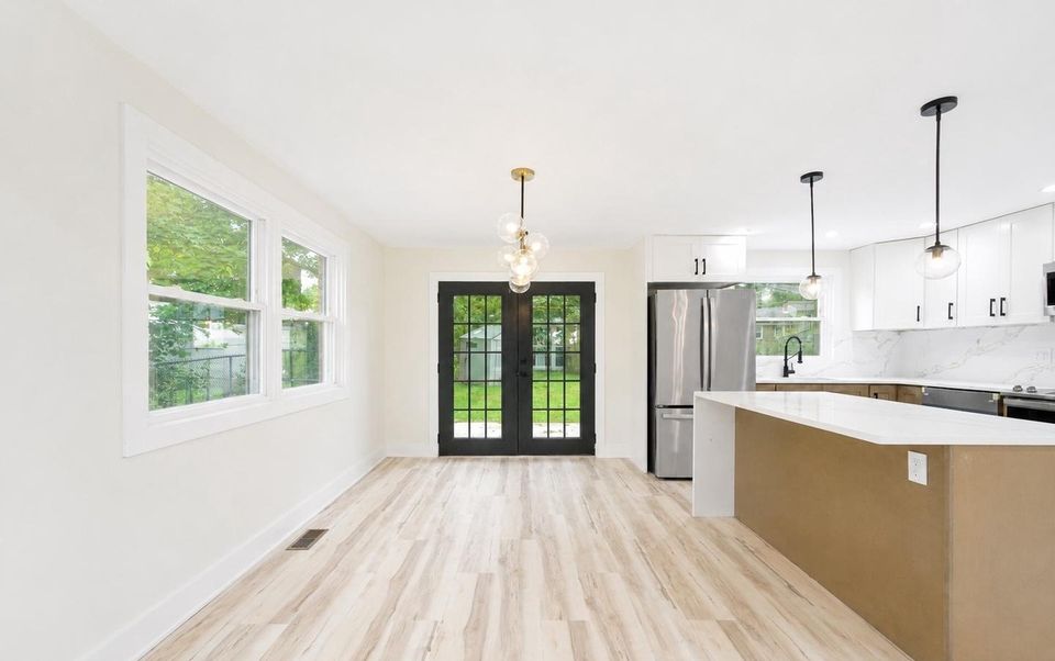 Dining area with French doors to the patio, chandelier and the kitchen island beyond.